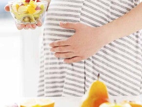 Maman enceinte tenant un bol de fruits pleins d'acide folique Maman enceinte tenant un bol de fruits pleins d'acide folique